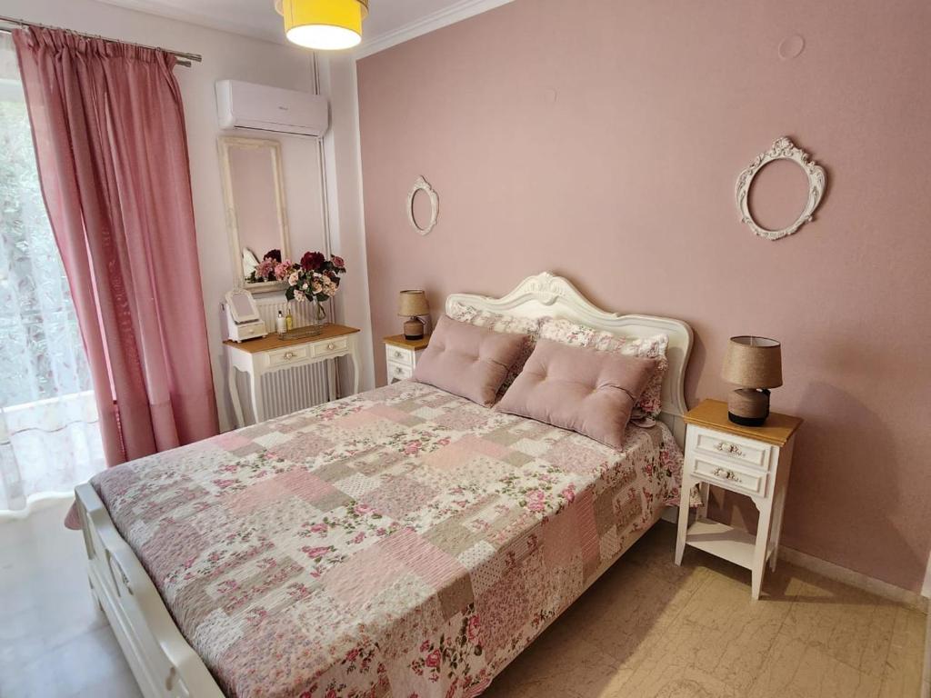 Dormitorio con cama con edredón rosa y espejo en Queen Aspri apartment 3' min to the beach!, en Antikyra