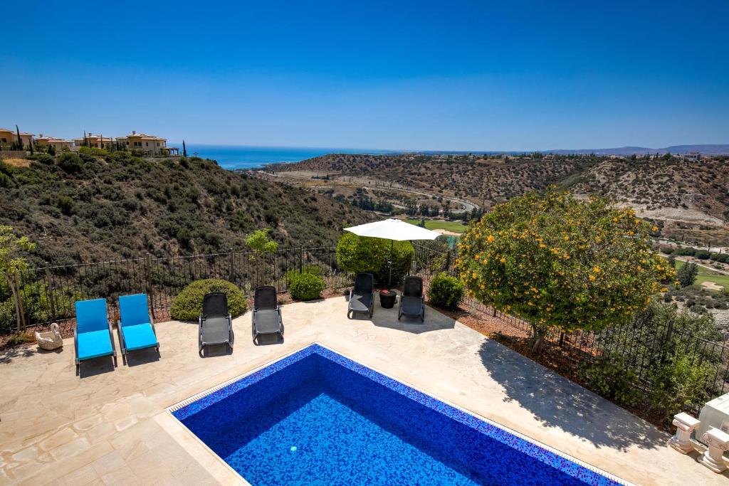 una piscina con sedie e vista sull'oceano di 3 bedroom Villa Melandra with private pool and sea views, Aphrodite Hills Resort a Kouklia