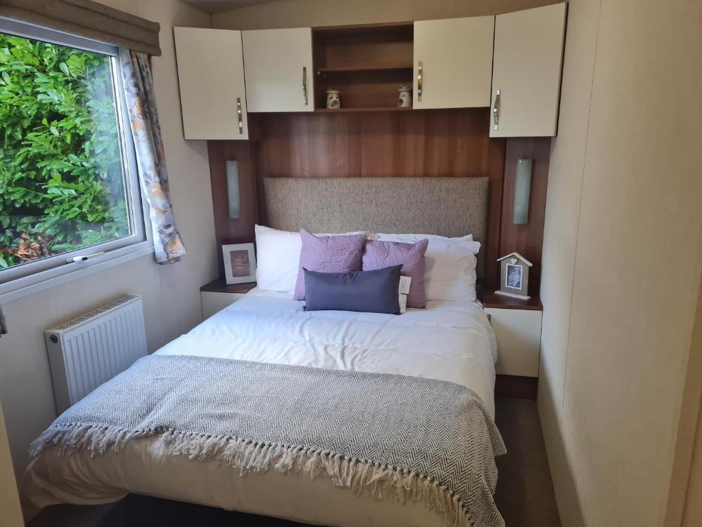 a bedroom with a bed with purple pillows and a window at Beautiful 3 bedroom holiday home Amazing views in Gisburn