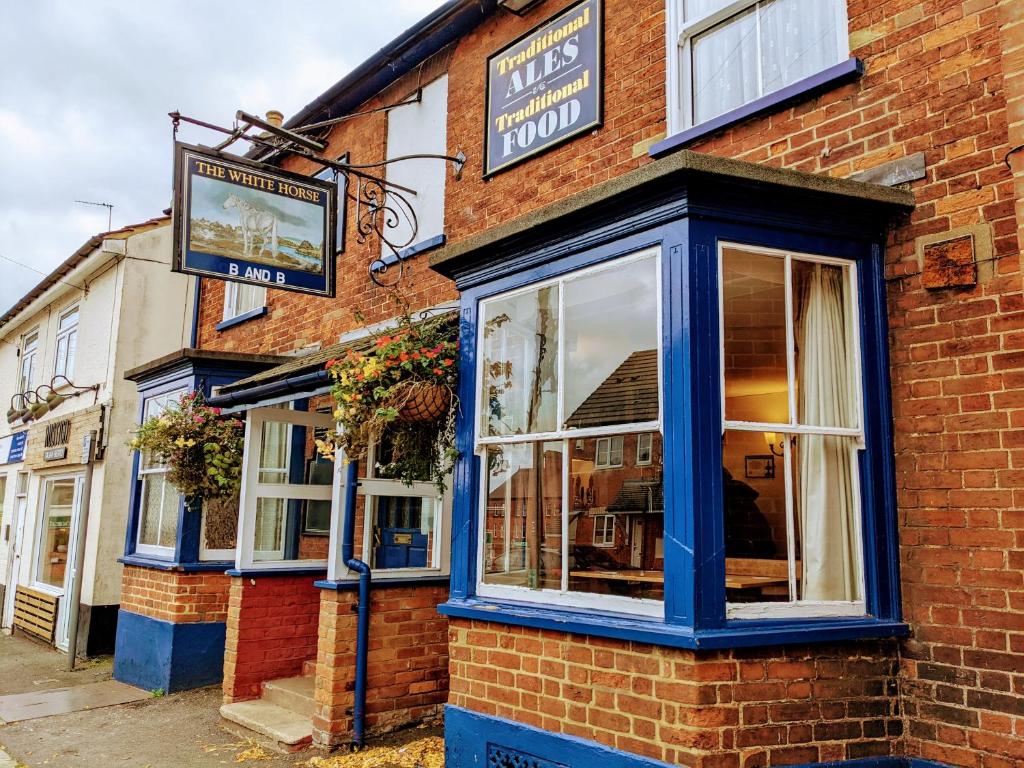 un edificio de ladrillo con un cartel en el costado en The White Horse, en Linslade