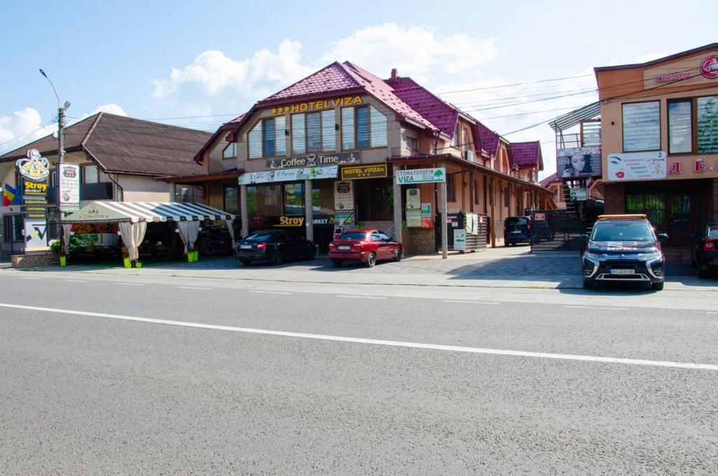 a town street with cars parked in front of buildings at Hotel VIZA in Solotvyno