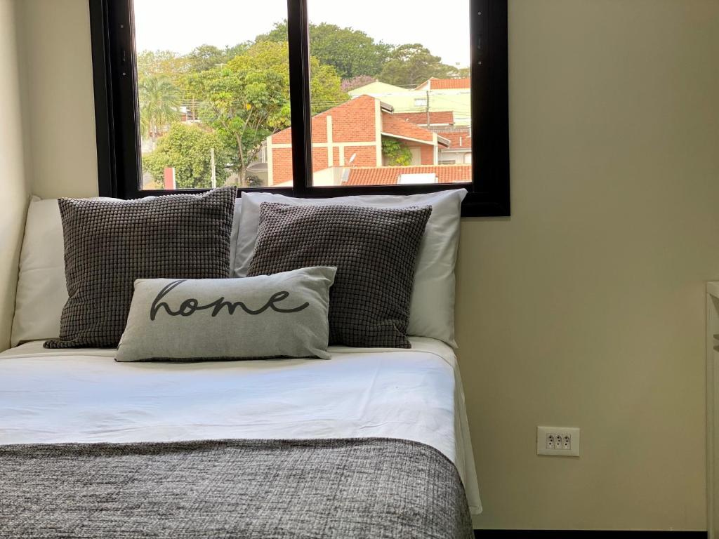 uma cama com uma almofada com a palavra casa sobre ela em 32A Estudio perto do HC em Marília
