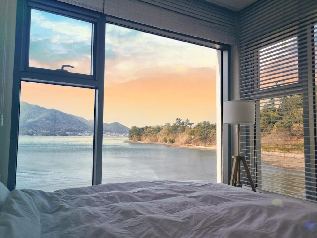 a bedroom with a large window with a view of the water at Namhae Bay 591 in Namhae