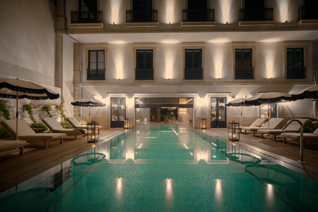 - une grande piscine dans un bâtiment avec des chaises dans l'établissement GA Palace Hotel & Spa, a XIXth-Century Villa, à Porto