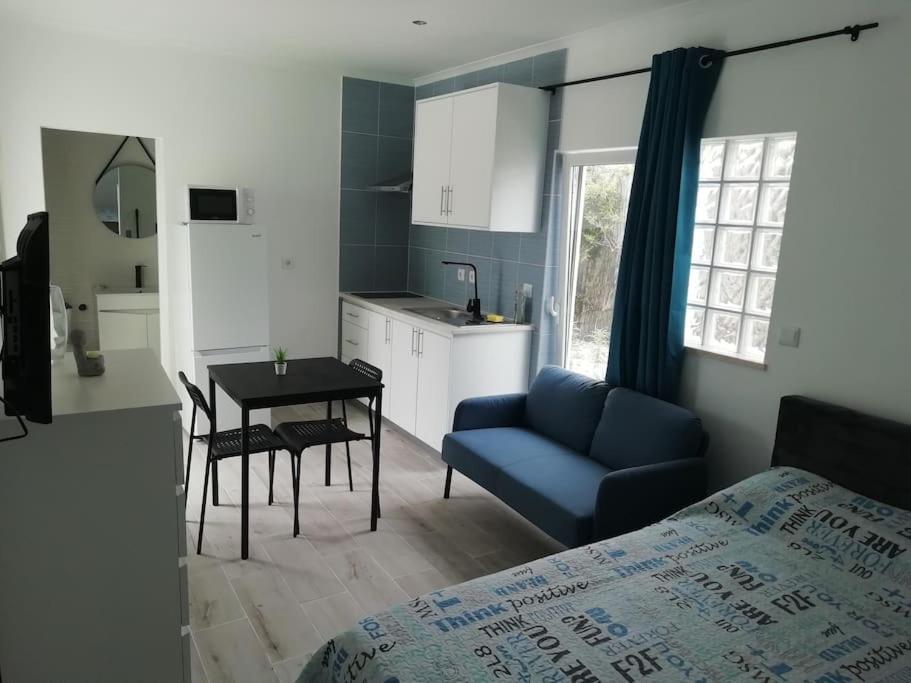 1 dormitorio con sofá azul, mesa y cocina en Refúgio Aconchegante, en Nadadouro