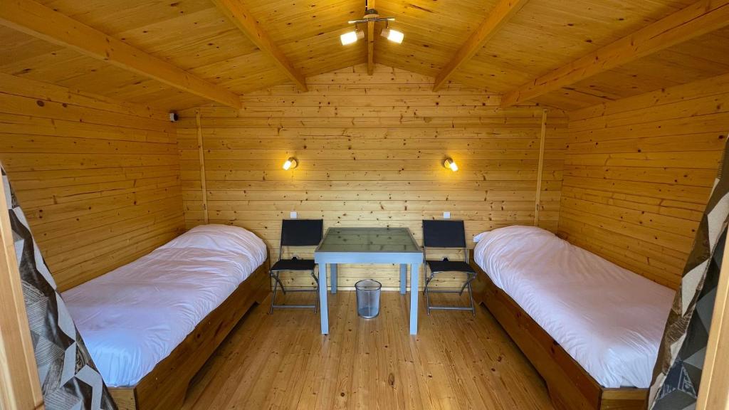 Zimmer mit 2 Betten und einem Tisch in einer Hütte in der Unterkunft Hébergement au bord de l'eau 