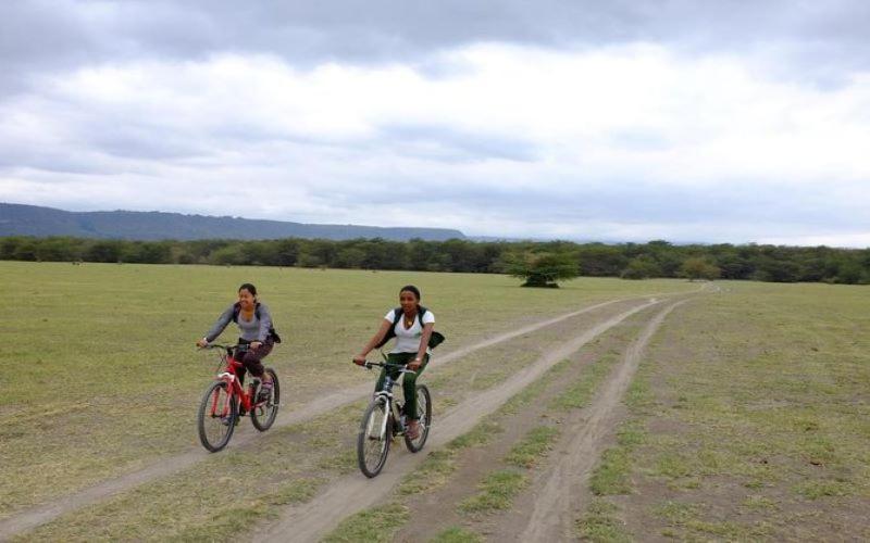 two people riding bikes on a dirt road at Kilimanjaro Mountain View Campsite 