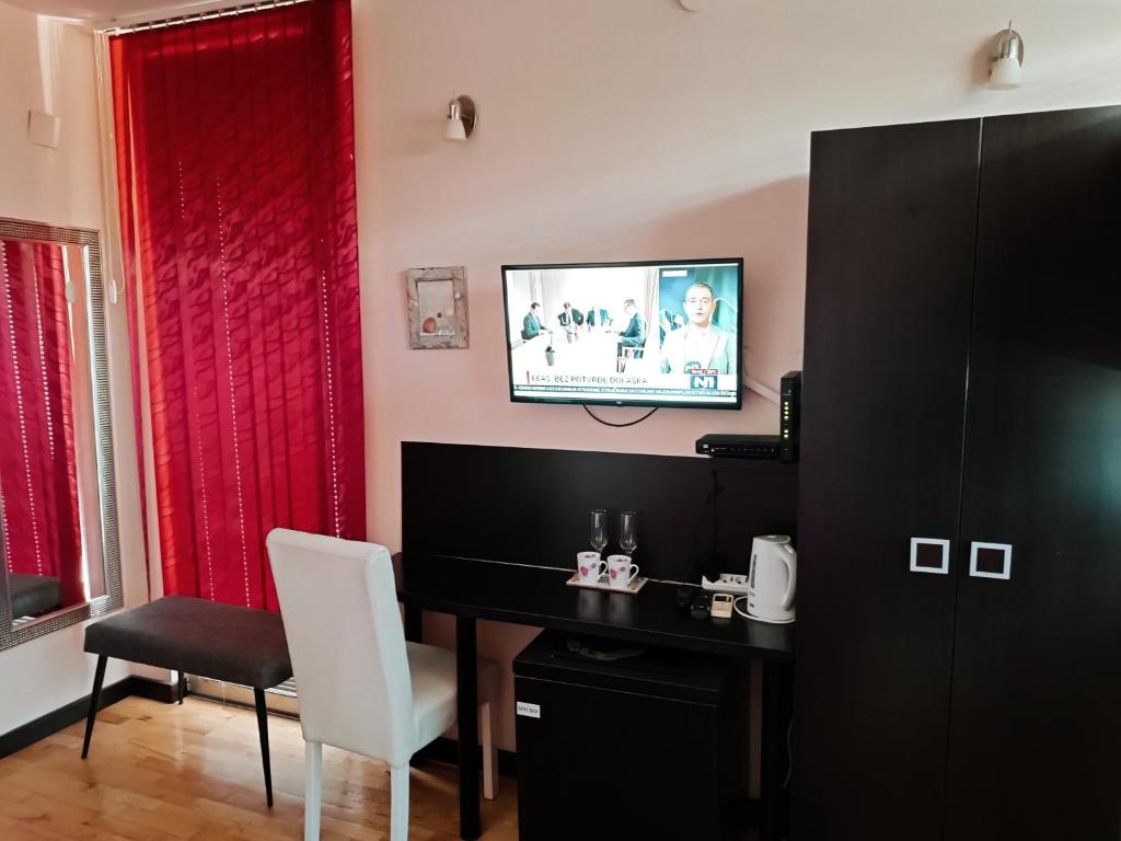 a room with a desk and a television on a wall at M Central Park in Niš