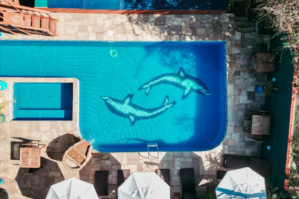 Deux dauphins peints sur le côté d'une piscine dans l'établissement Pousada Villa Atlântica, à Camburi