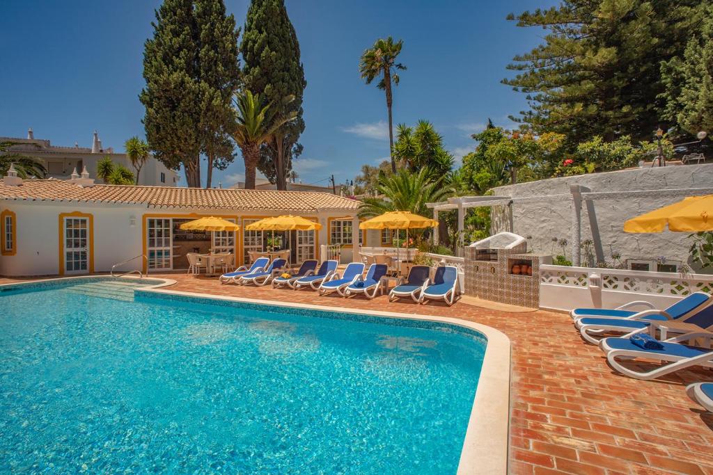 a swimming pool with lounge chairs and umbrellas at 2 Bed Flat - Sleeps 4 - Pool - Terrace - Parking in Luz