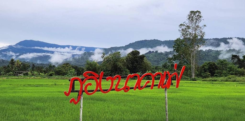 a red sign in the middle of a field at ภูอิงนาคาเฟ่&รีสอร์ท in Ban Wang Takhrai