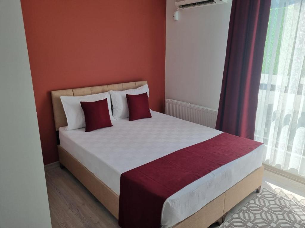 istanbul airport family suites hotel في Arnavutköy: غرفة نوم بسرير ومخدات حمراء وبيضاء