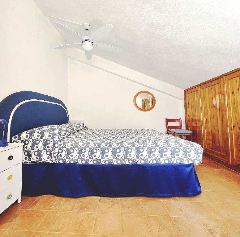 a bedroom with a blue bed and a ceiling fan at Praialonga - Attico con terrazzo in Le Castella