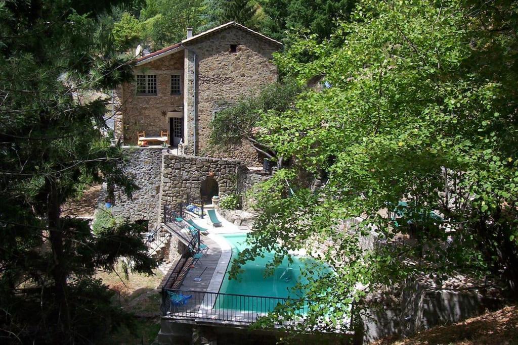 - une piscine en face d'une maison en pierre dans l'établissement Gîte de la perge haute, à Vals-les-Bains
