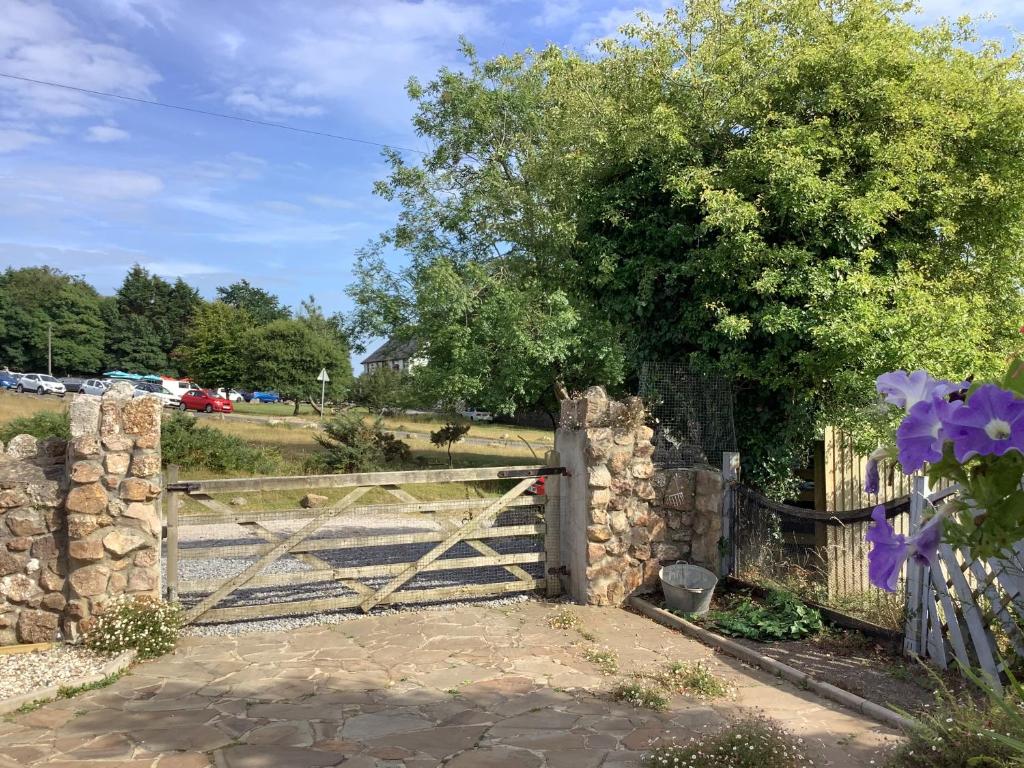 una puerta de madera con una valla de piedra y un árbol en Ger Tŷ en Swansea