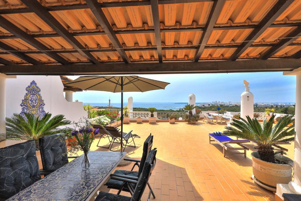 een patio met een tafel en stoelen en een parasol bij Casa Sol in Ferragudo