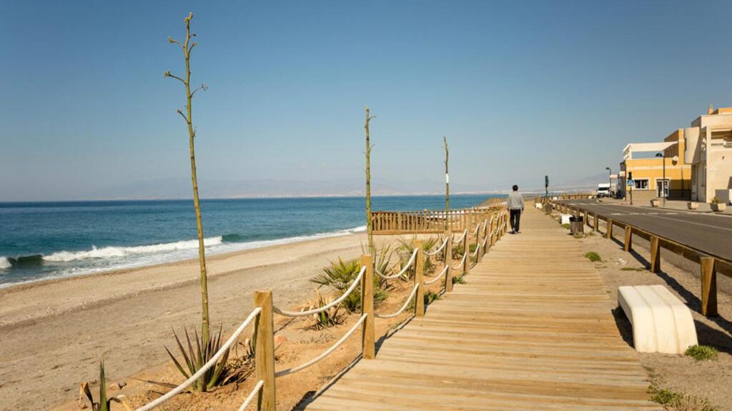 un hombre caminando por una pasarela de madera hasta la playa en Apartamento Mar Azul Ref 6364, en Torrevieja