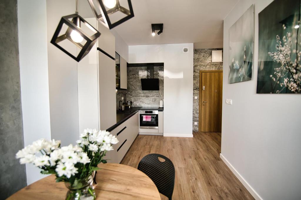 a kitchen and dining room with a wooden table and flowers at Just 5 by Housine in Zator