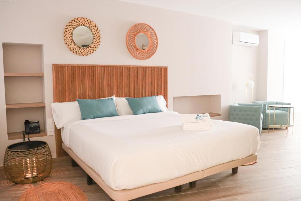 a bedroom with a large white bed and two mirrors at HOTEL NARCEA in Santa Pola