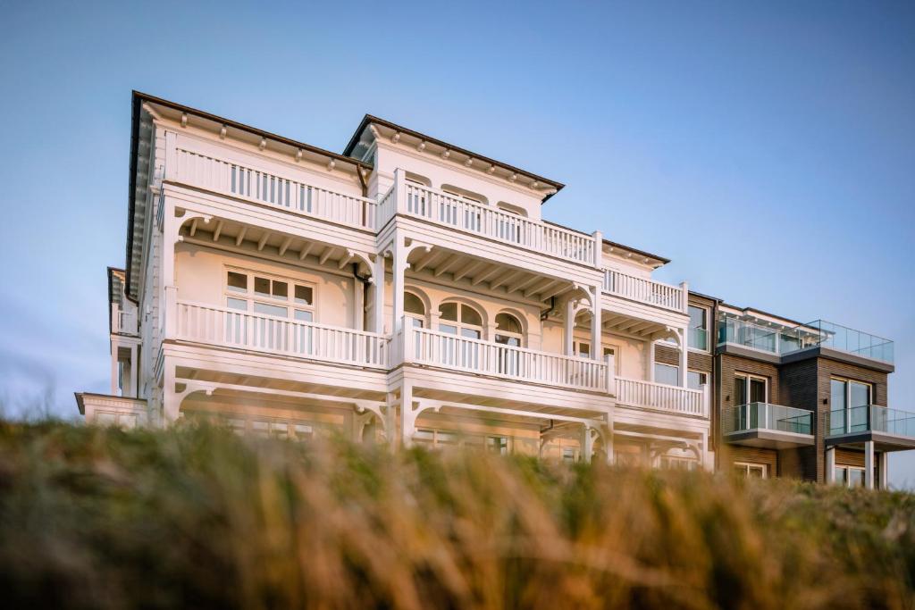 uma grande casa branca com uma varanda em 1884 Norderney em Norderney