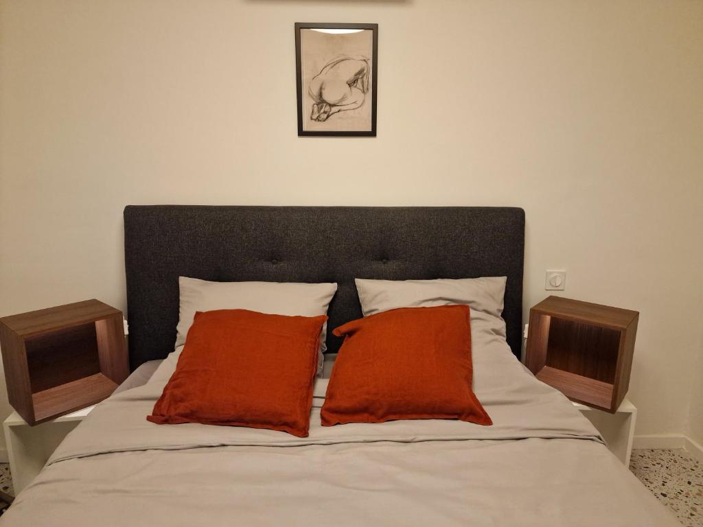a bed with two orange pillows on top of it at maison PING ,en face des arènes in Béziers