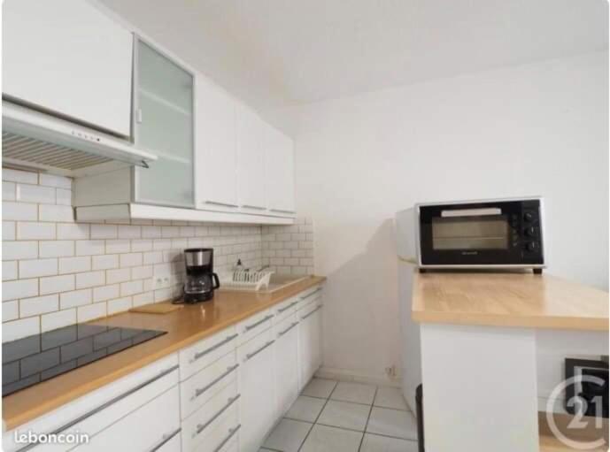 La cuisine est équipée de placards blancs et d'un four micro-ondes noir. dans l'établissement Vacances à la mer, à La Grande Motte