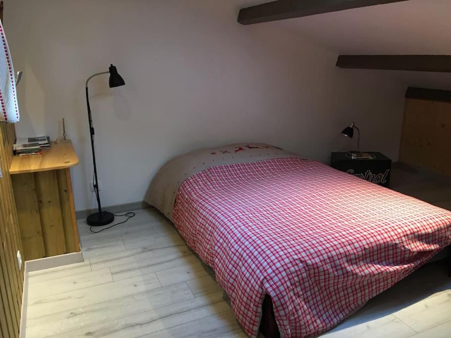 a bedroom with a bed with a red and white blanket at Gîte Le Buron in Chazelles