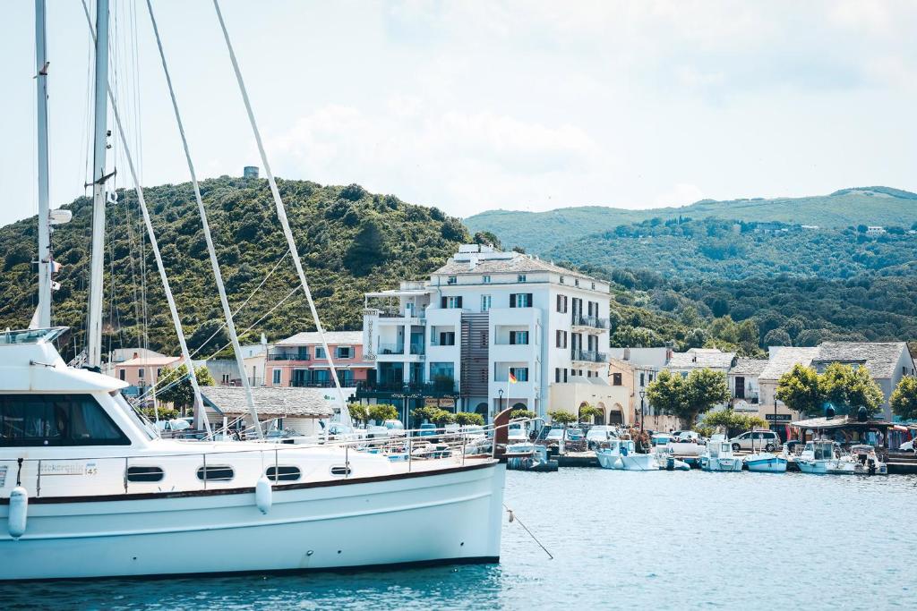 un velero atracado en un puerto deportivo con casas en Marina D'oro, en Macinaggio