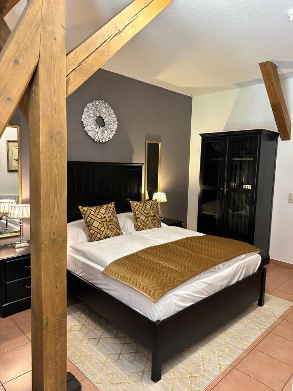 ein Schlafzimmer mit einem großen Bett mit einem Holzrahmen in der Unterkunft Hotel Henriettenhof Weimarer Land, Weimar-Bad Berka in Bad Berka