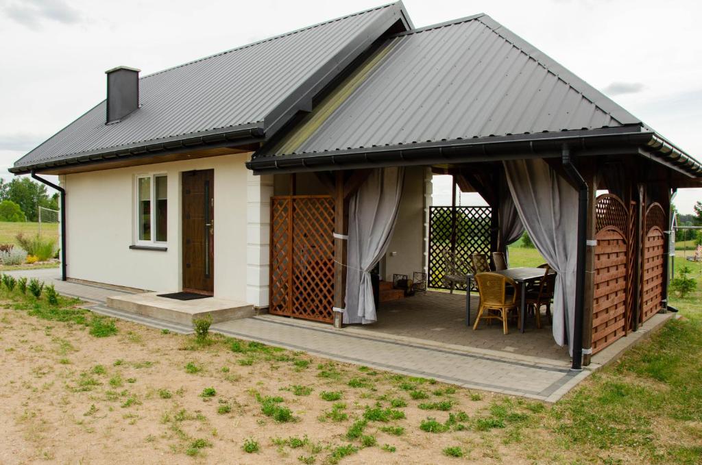 a small white cottage with a black roof at Domki na Wzgórzu - Rospuda - Domek z sauną in Filipów