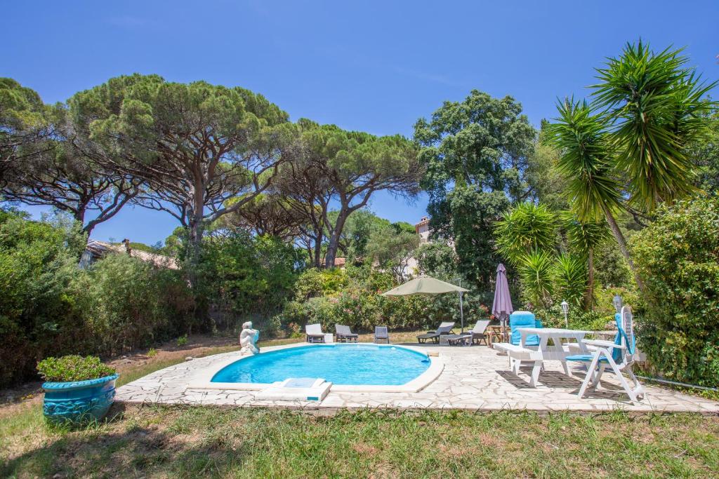 uma piscina com mesa, cadeiras e árvores em Villa Regina 500 métres de la plage em La Garonnette-Plage