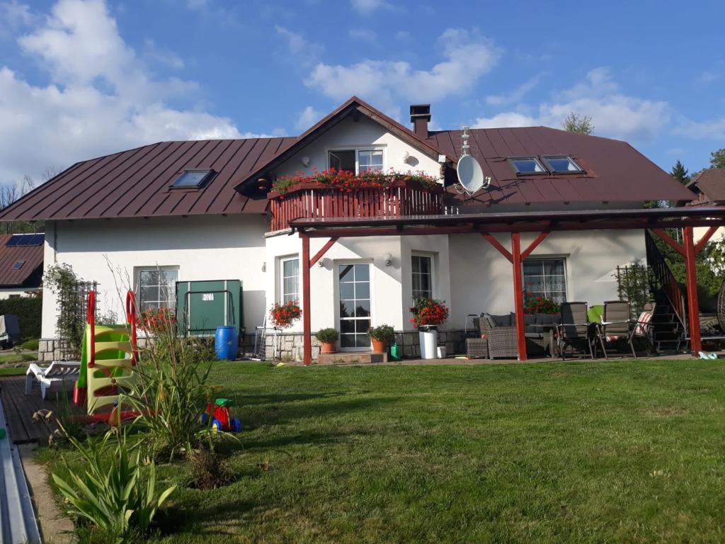 ein weißes Haus mit einem Balkon und einem Hof in der Unterkunft Penzion Irena in Strážné