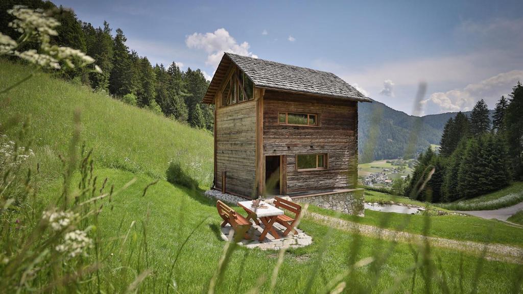 a wooden cabin on a hill with a table and two chairs at Burgfrieder Mühle in Rasun di Sopra