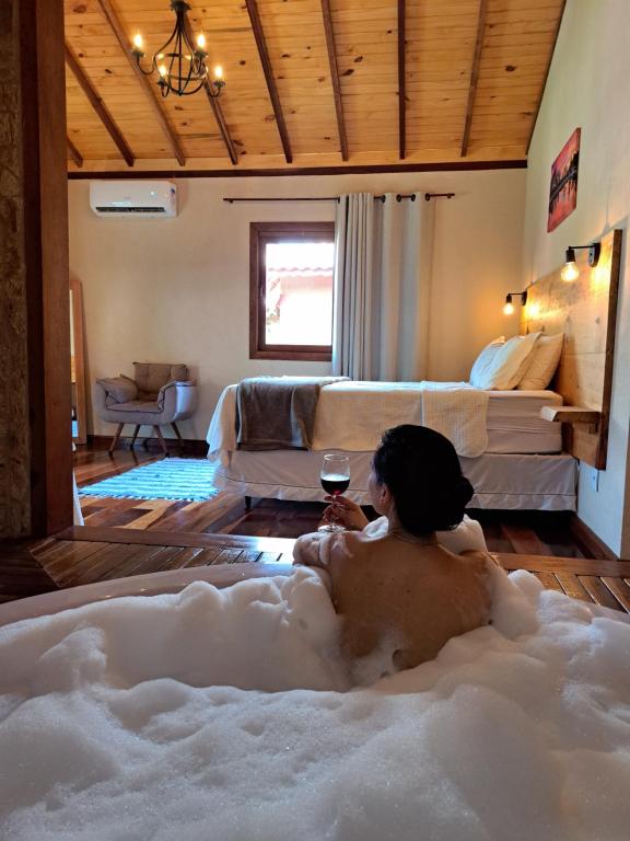un homme assis dans une baignoire avec un verre de vin dans l'établissement Pousada Vale da Cachoeira, à Visconde de Mauá