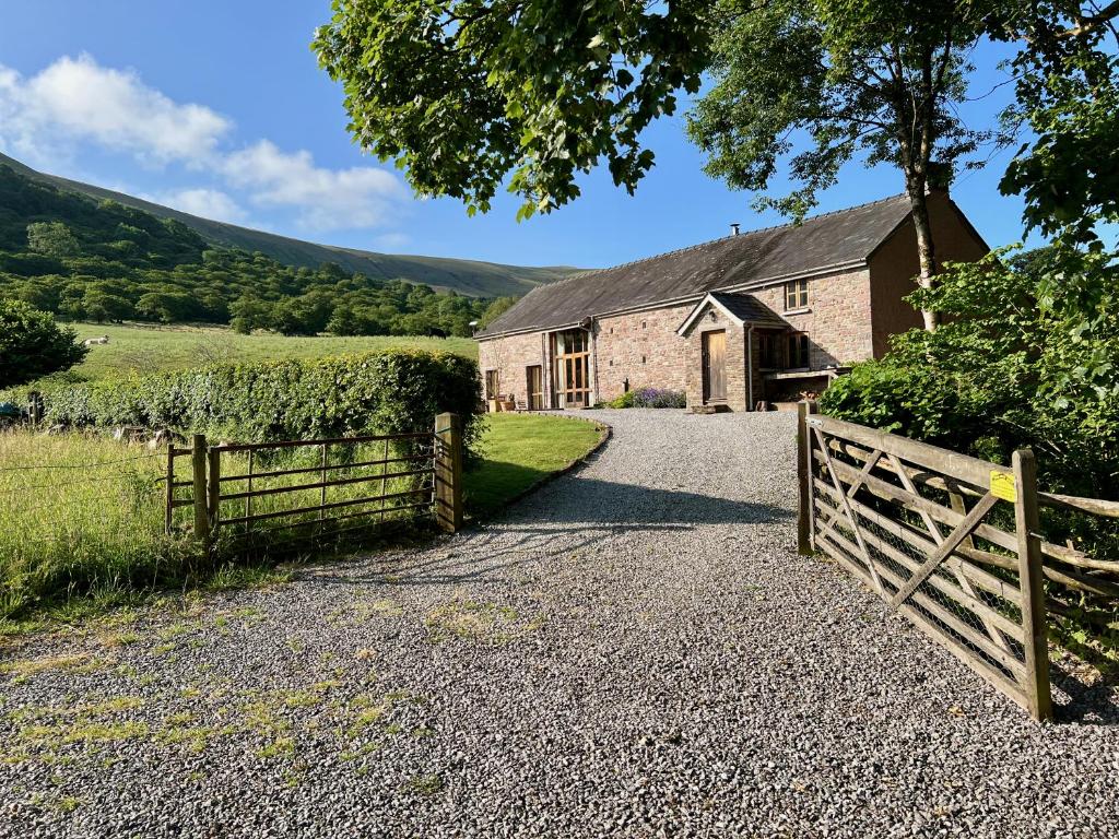 eine alte Scheune mit einem Zaun und einem Tor in der Unterkunft Baddegai Holiday Cottage in Brecon