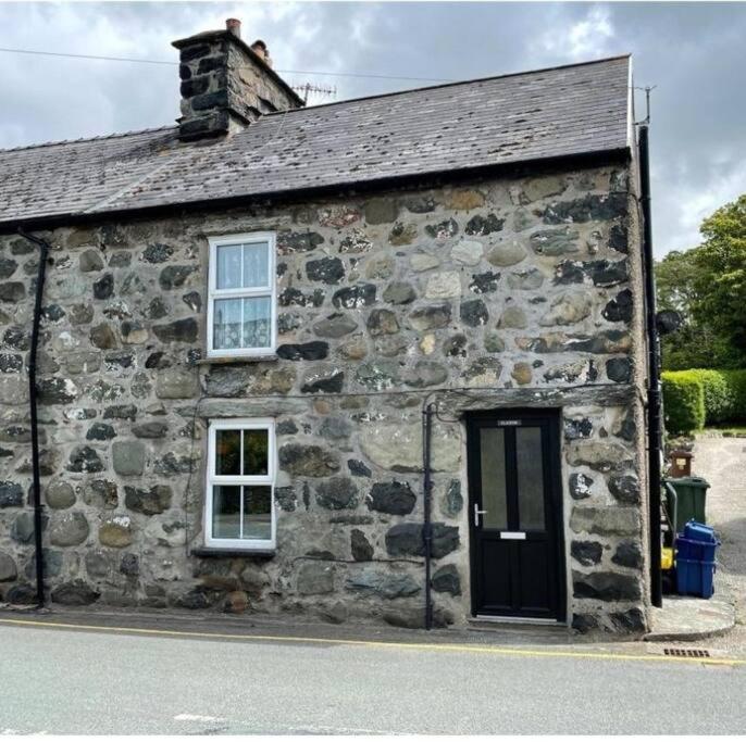 un vecchio edificio in pietra con finestra e porta di Glasfor Cottage a Llwyngwril