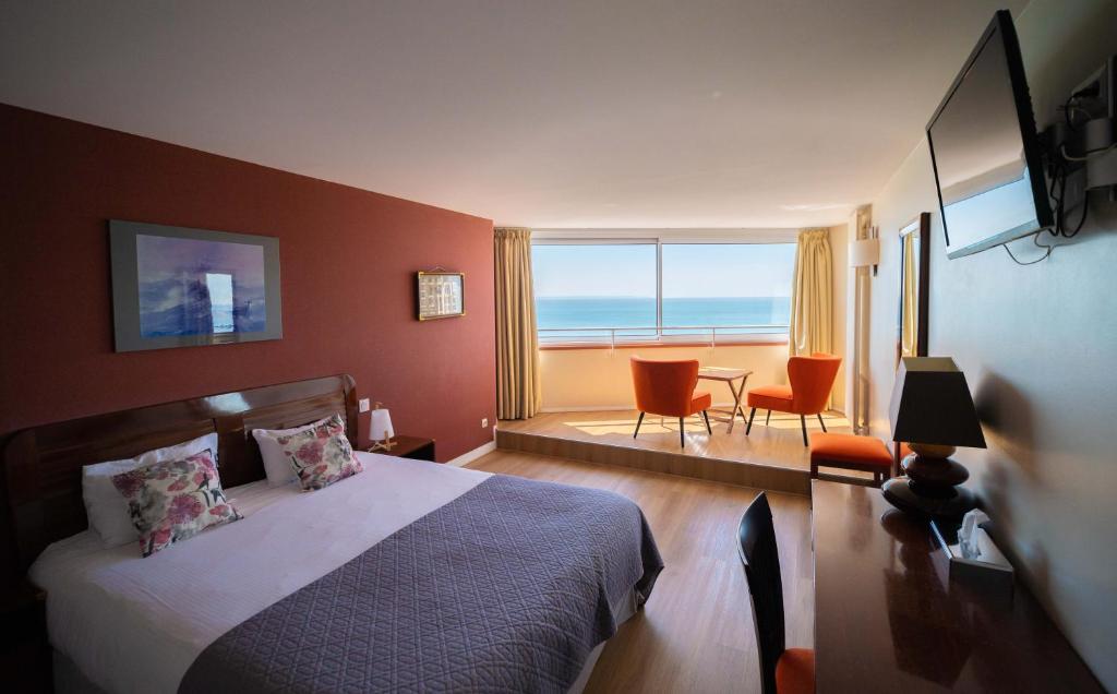 a bedroom with a bed and a view of the ocean at LOGIS HOTEL - La Petite Rade in Le Havre