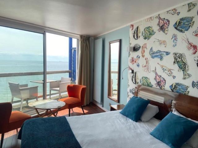 a bedroom with a bed and a view of the ocean at LOGIS HOTEL - La Petite Rade in Le Havre