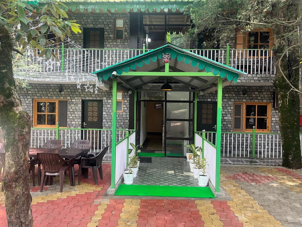 a gazebo with a table and chairs in front of a building at Cedar Woods Resort in Nainital