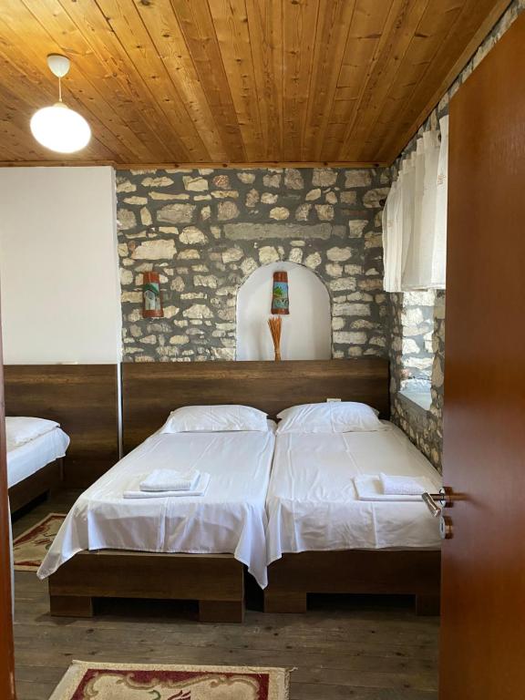 1 dormitorio con 2 camas y techo de madera en Aria Baci Guest House, en Berat