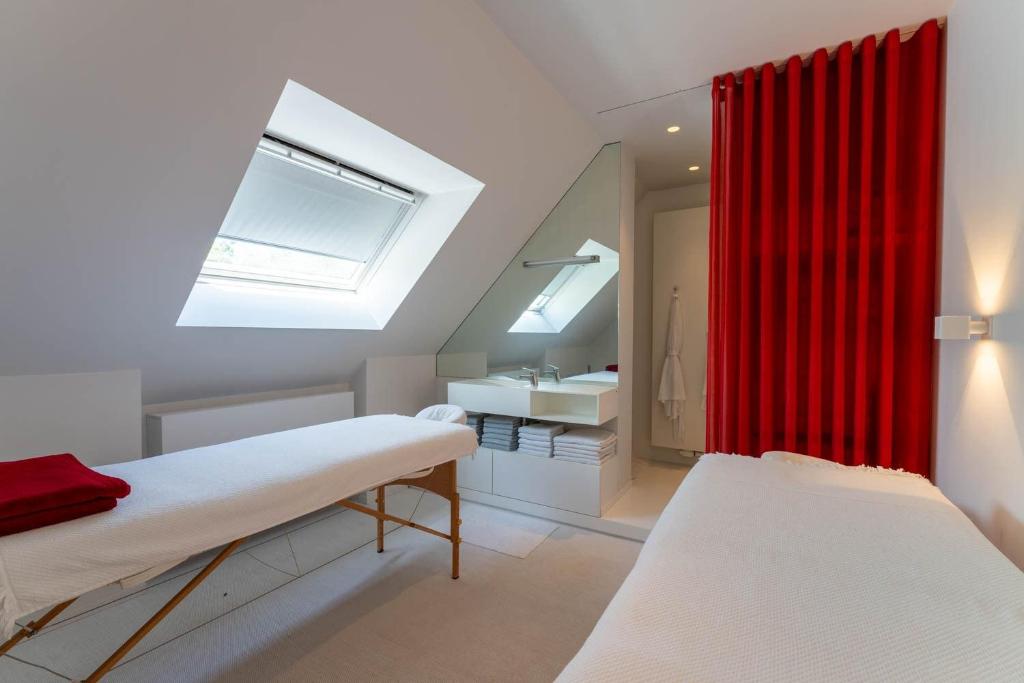 ブランケンベルヘにあるPolderlichtのベッド2台と赤いカーテンが備わる客室です。