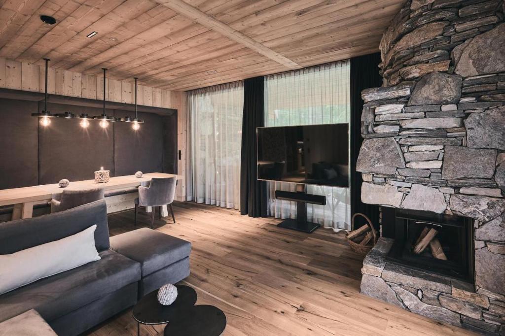 a living room with a couch and a stone fireplace at Waldchalet mit Jacuzzi in Racines