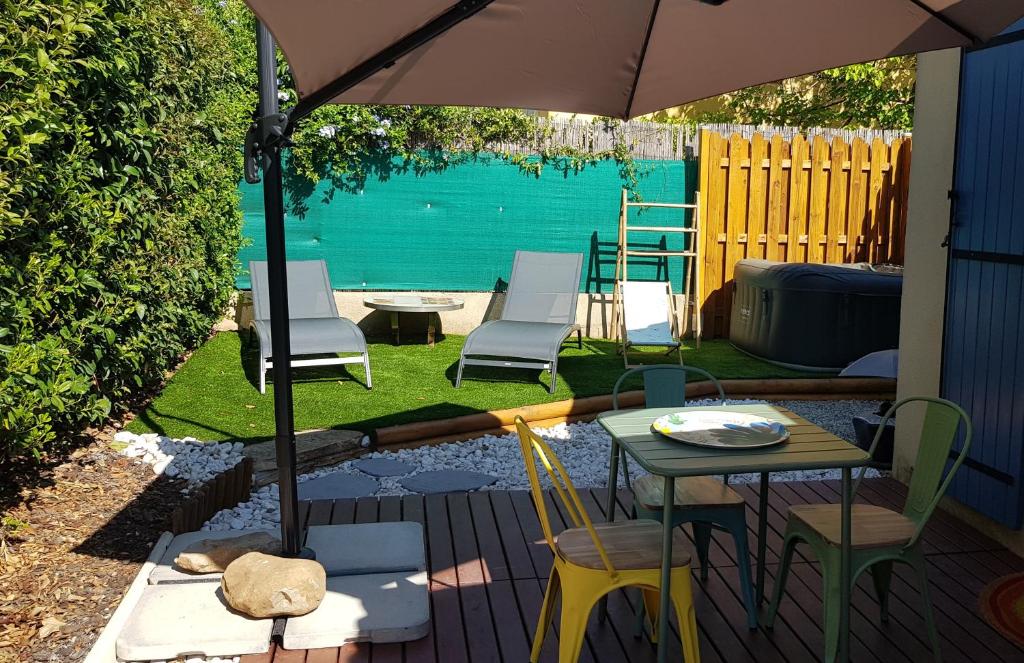 a patio with a table and chairs and an umbrella at Chez Florence et Bruno in Saint-Cyr-sur-Mer