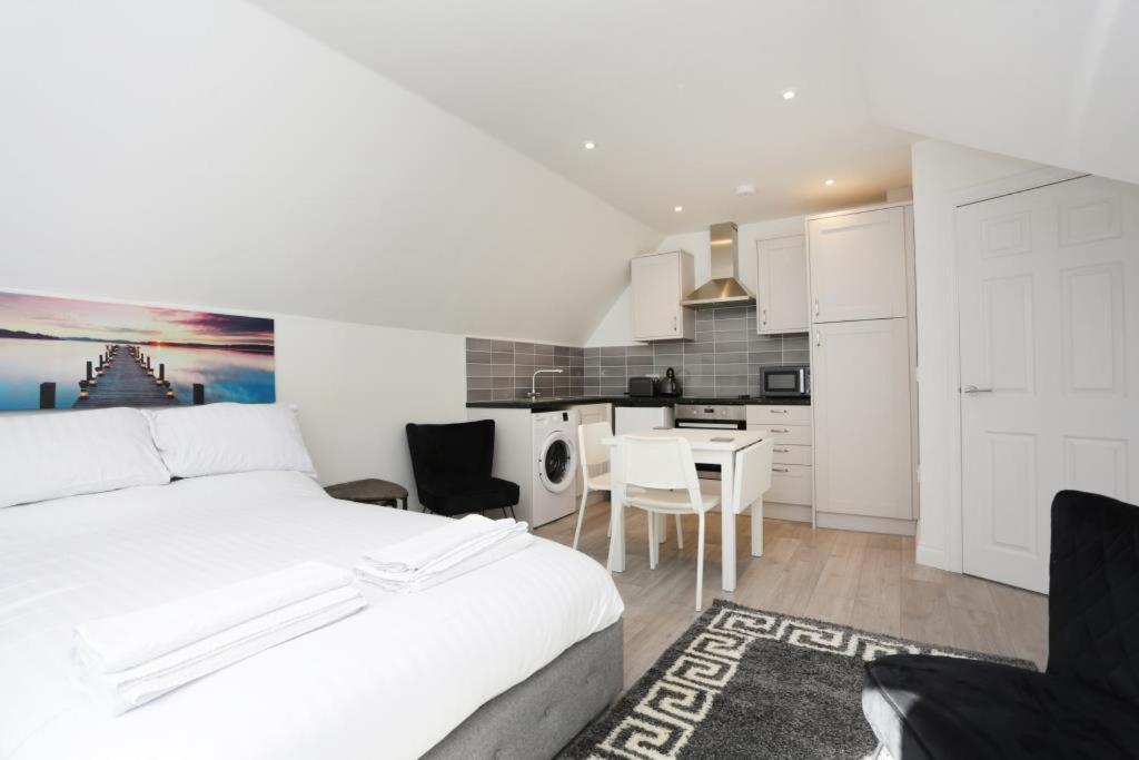 1 dormitorio con 1 cama blanca y cocina en The Stafford Apartments, en Bournemouth