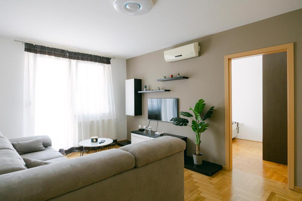 uma sala de estar com um sofá e uma televisão em Ladenta apartman*** em Zagreb