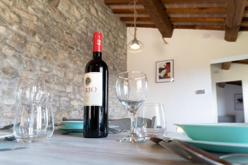 eine Flasche Wein auf einem Tisch mit Brille in der Unterkunft Rustic House, con patio e giardino, Assisi centro in Assisi