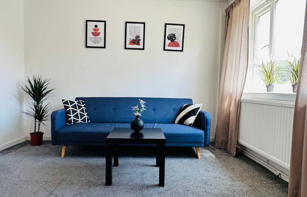 a blue couch in a living room with a table at Cosy Flat Close To East Dulwich Station in London