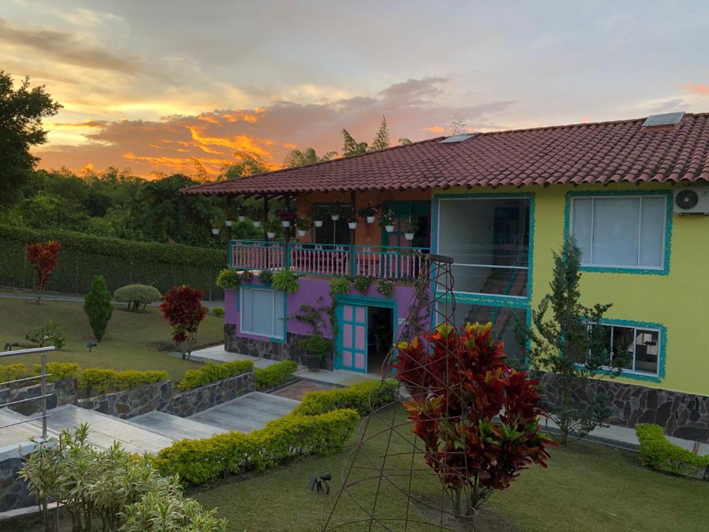 a house with a sunset in the background at Encanto Cafetero Montenegro in Pueblo Tapao