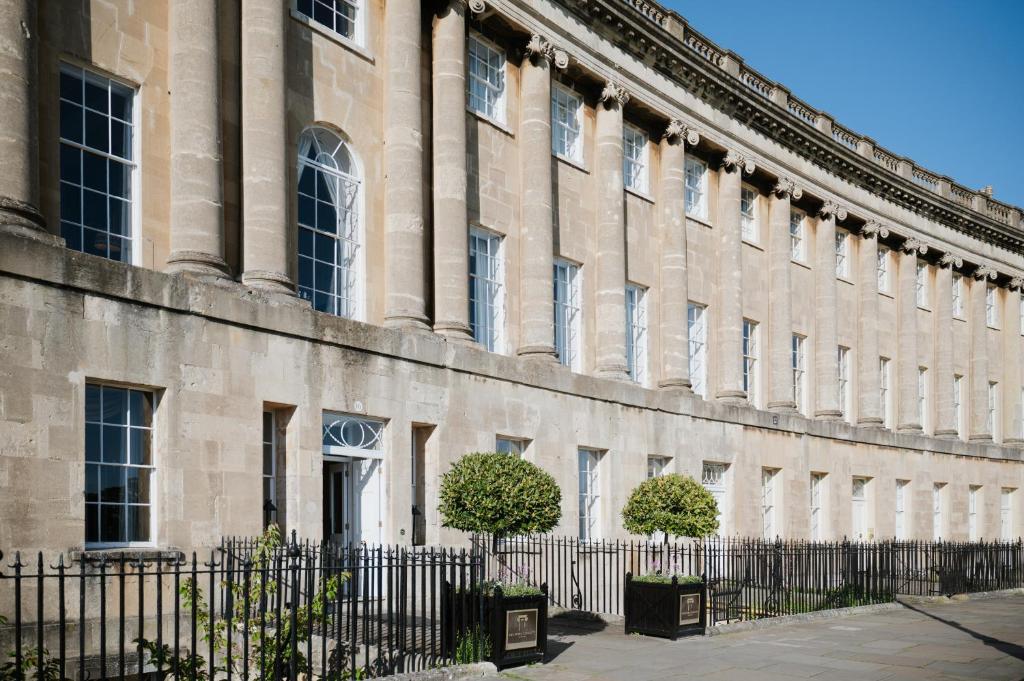 ein großes Gebäude mit einem Zaun davor in der Unterkunft The Royal Crescent Hotel & Spa in Bath