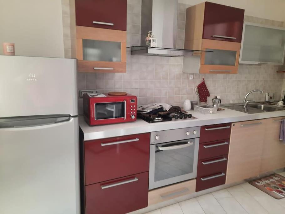 W kuchni znajduje się biała lodówka i czerwona kuchenka mikrofalowa. w obiekcie Stylish Loft Trivano Cagliari 2 beds/2 bath w Cagliari